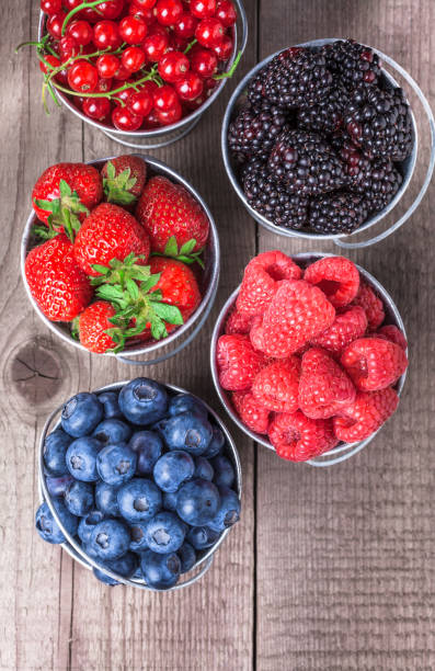 istock Berries close up assortment overhead in tin cans on wooden table 927185758