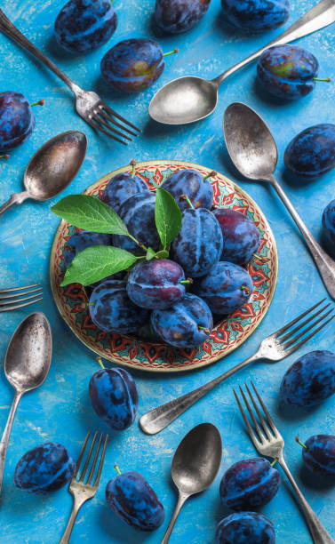 istock Plums and leaves overhead on plate with forks and spoons 927188210