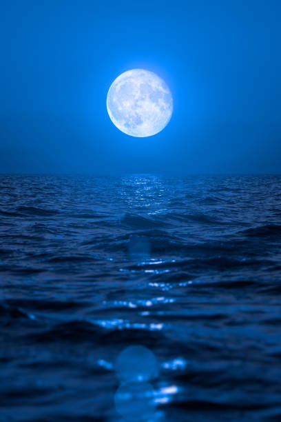 istock Full moon rising over empty ocean at night 927191190