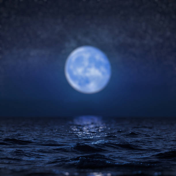 istock Full moon rising over empty ocean at night, blur background 927193712