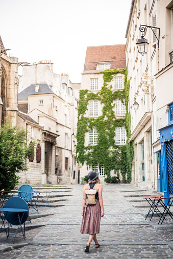 A young woman exploring the empty streets of Paris France in the early morning.