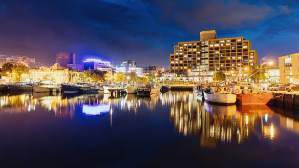 Panoramic view of Hobart skyline at night with reflections in the calm water of the marina. Hobart, Tasmania, Australia.