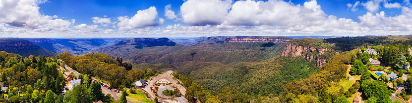 Wide panorama of Blue Mountains Three sisters, canyon and Mt Solitary from Katoomba regional tourist town on a sunny summer day.