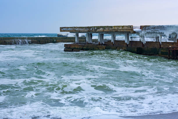 istock Stormy day at winter beach. Icy waves breaking at snow covered rocks. 927241000