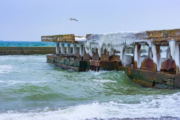 istock Stormy day at winter beach. Icy waves breaking at snow covered rocks. 927241342