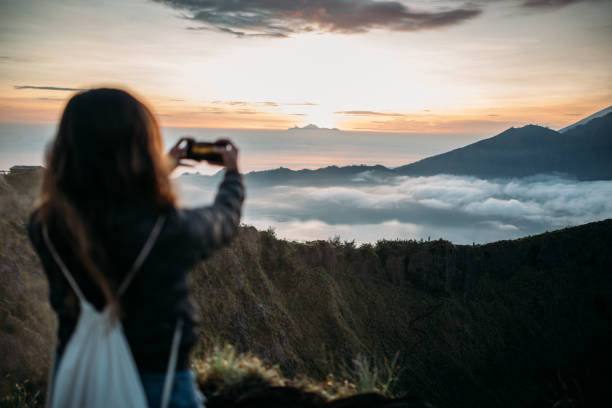 Young women hiker making photos of Mt. Batur and Mt. Agung, Bali, Indonesia