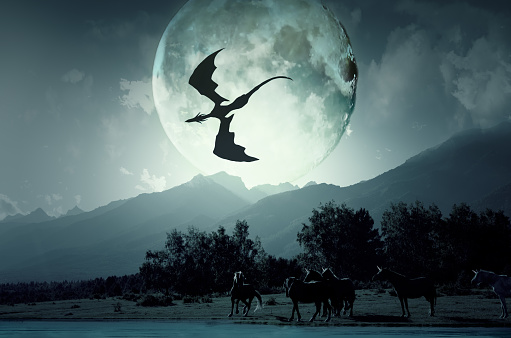 The dragon flies over the unicorns in the background of the huge full moon. Down near the river grazing unicorns, flashing his horn.
