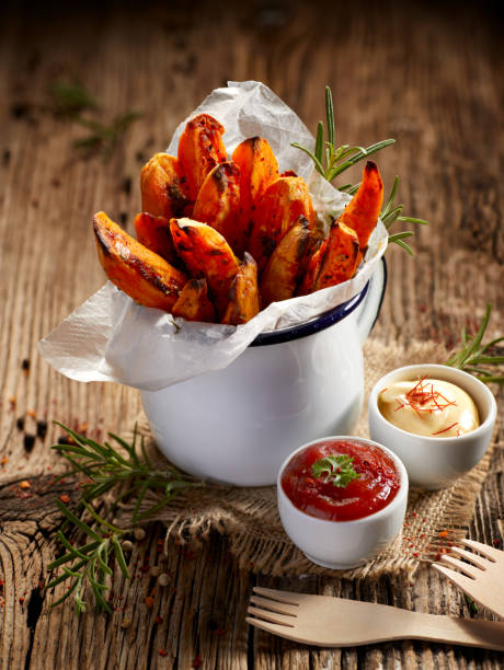 Sweet potato fries seasoned herbs and sea salt in enamel mug on a wooden table Sweet potato fries seasoned herbs and sea salt in enamel mug on a wooden table, delicious and healthy vegetarian snack sweet potato french fries stock pictures, royalty-free photos & images