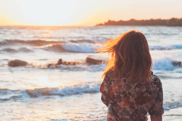 istock Young woman enjoying sunset and waves at the beach 927267156