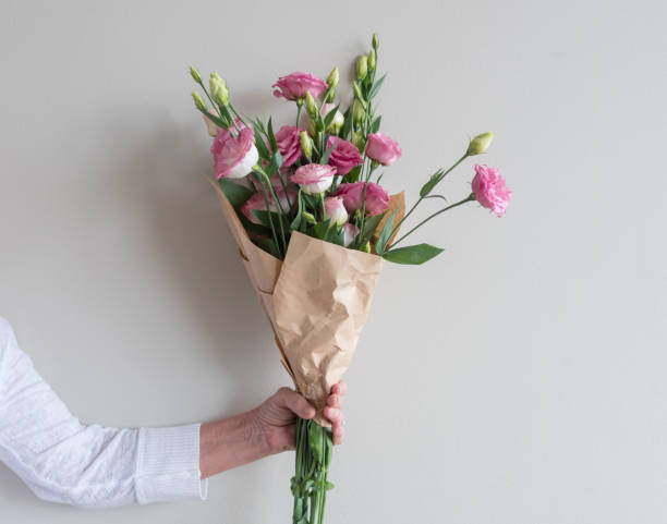 frau hand mit rosa blumenstrauß - lisianthus stock-fotos und bilder