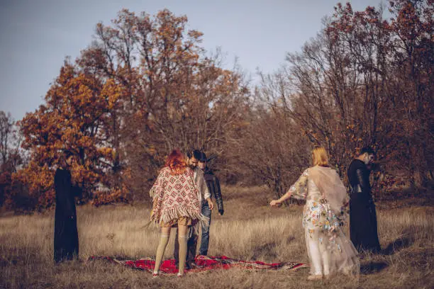 A group of masked and dressed up people standing in an autumn field. Sect concept