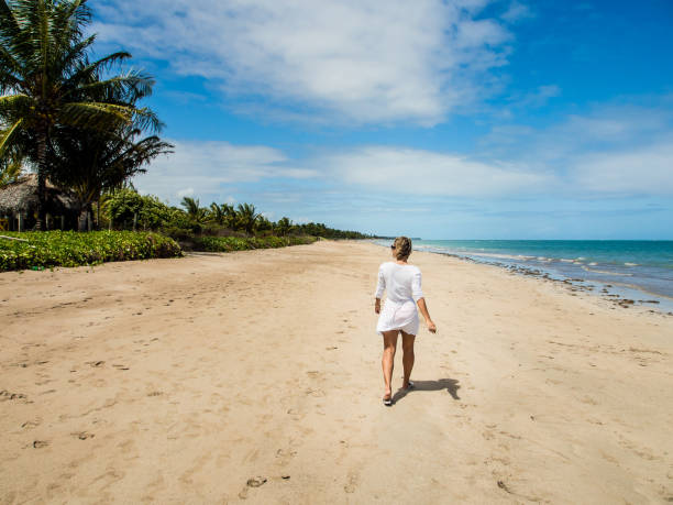 istock attractive woman walking along beach view on a summer day 927299382