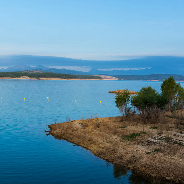 Mountain lake in Spain early in the morning. Spanish landscape at sunrise, hills, water, beach and sunlight