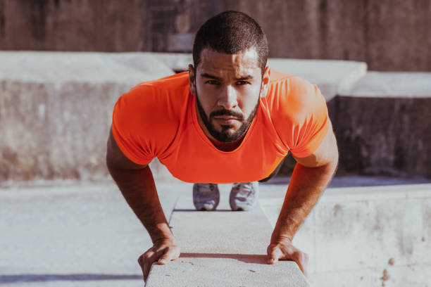 skoncentrowany młody człowiek robi pompki na krawężniku - exercising men push ups muscular build zdjęcia i obrazy z banku zdjęć