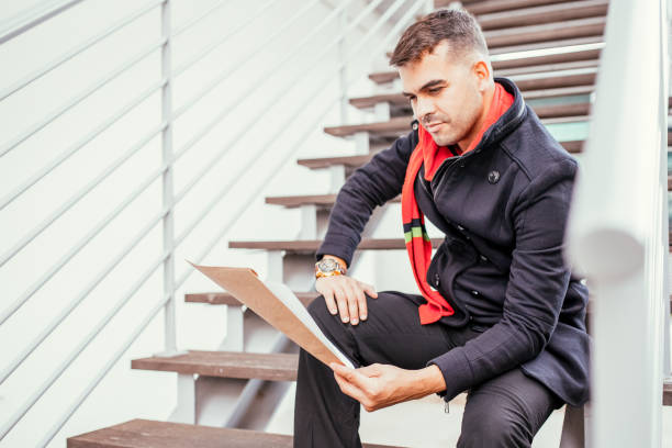 istock Concentrated young man reading papers on stairs 927320156