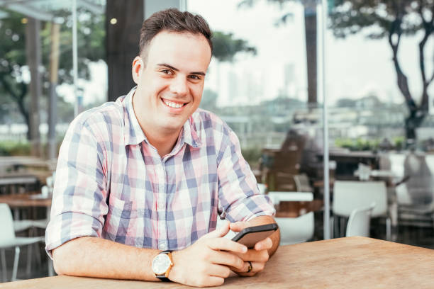 istock Smiling Man Using Smartphone in Outdoor Cafe 927320578
