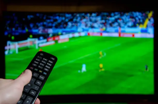 Photo of Watching Football on TV and using remote controller.