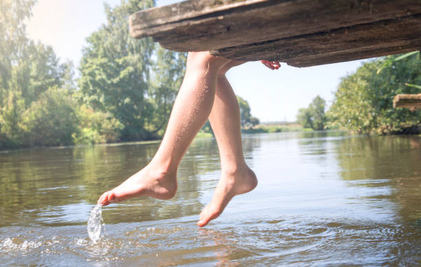istock Women's feet splashing in the pool water 927328392