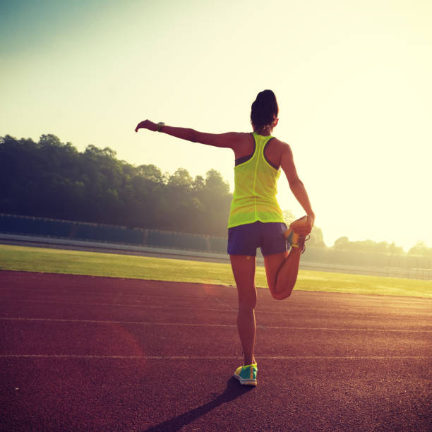 istock Young woman stretching legs before run during sunny morning on stadium 927339770