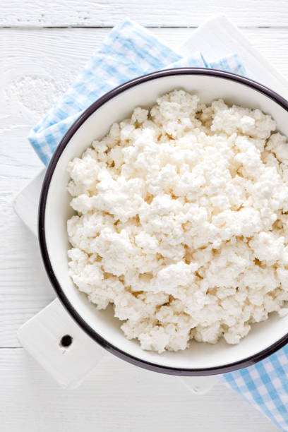 istock Cottage cheese, curd on white wooden rustic table, top view 927355244