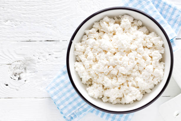 istock Cottage cheese, curd on white wooden rustic table, top view 927355336