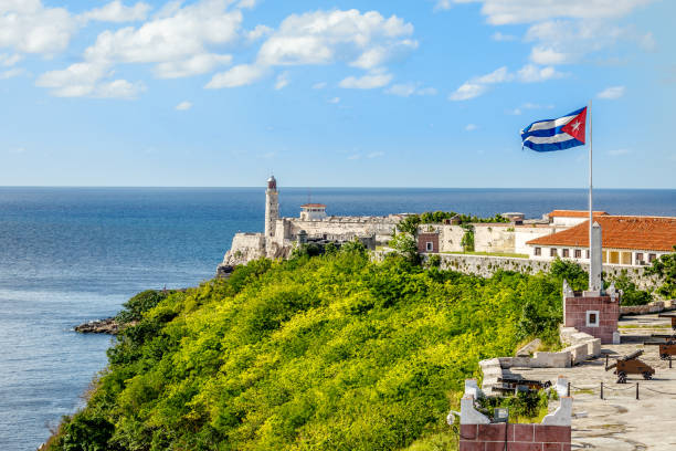 el morro forteresse espagnole avec phare, canons et un drapeau cubain en avant-plan de th, avec la mer en arrière-plan, la havane, cuba - fort bay photos et images de collection