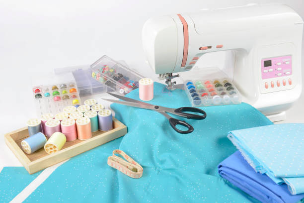 istock Sewing machine and colorful thread rolls, scissors, fabric and accessories for sewing on white background, Sewing and needlework concept. (Selective Focus) 927359442