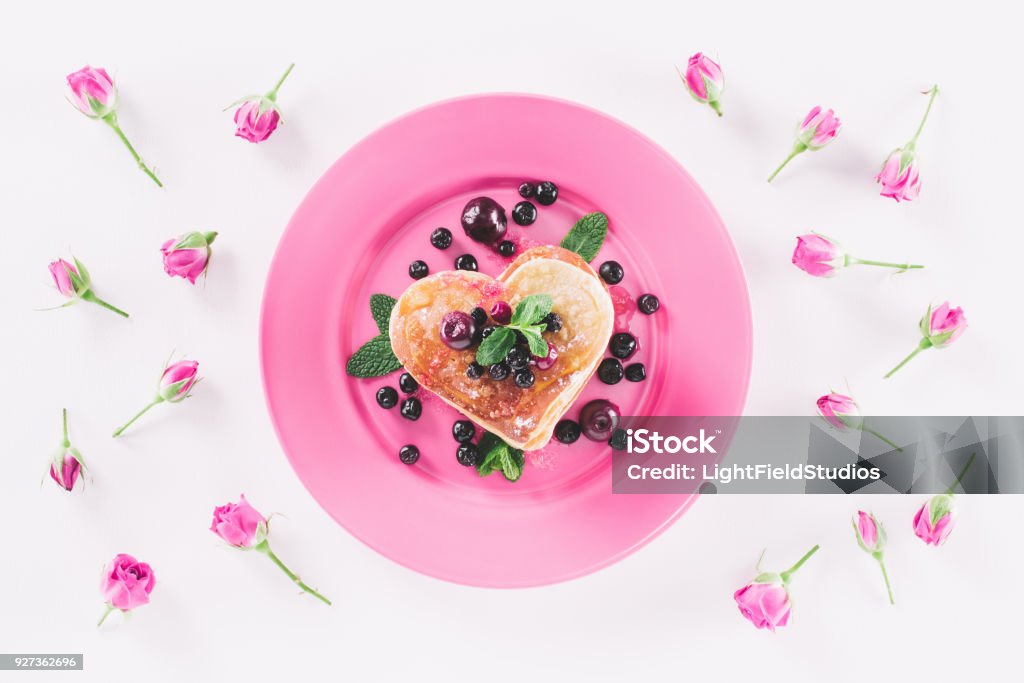 top view of heart shaped pancake and pink roses isolated on white, valentines day concept Baking Stock Photo