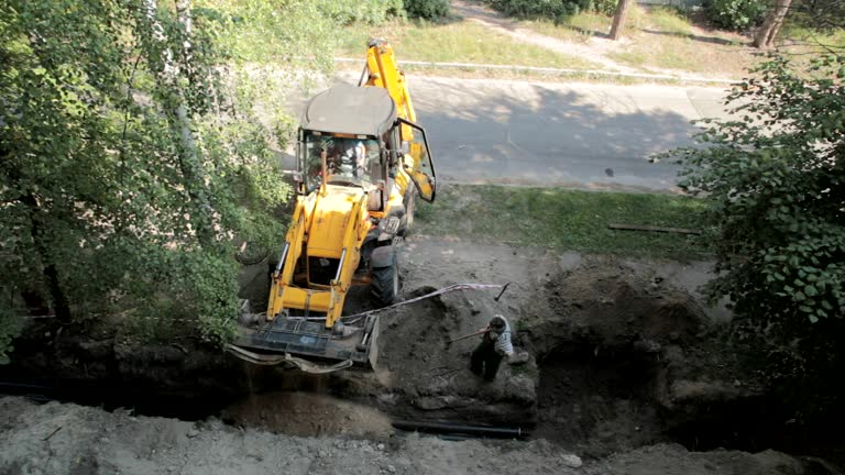 Bulldozer and a worker bury a trench.