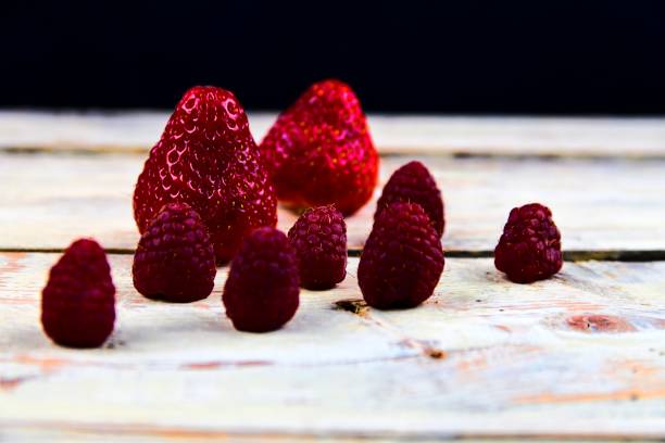 istock Strawberries and raspberries on rustic white wooden background. White and black background. Dark image 927375496