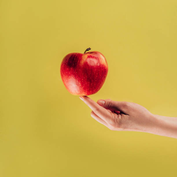 istock partial view of woman holding apple on finger 927388342