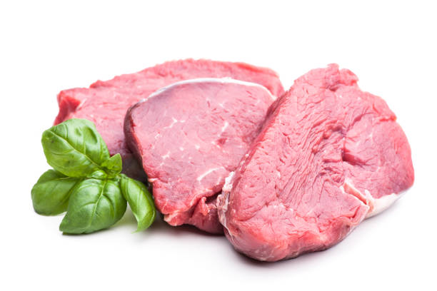 Three slices of raw meat on white with garnish stock photo