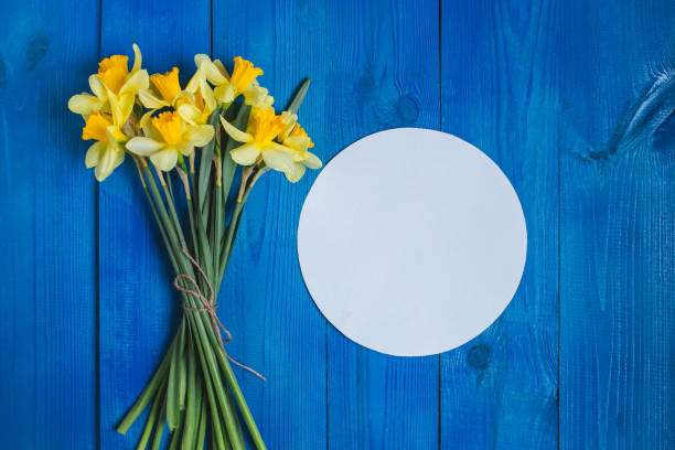 istock Spring easter background with daffodils bouquet on blue wooden table 927390786