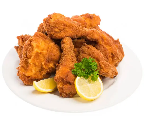 Photo of fried chicken with lemon and parsley on a white plate