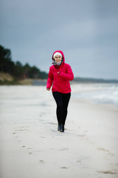 istock Young woman running, jumping on beach 927398652