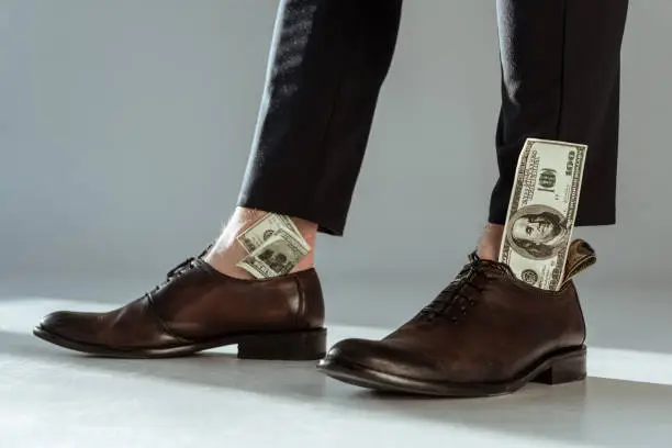 Photo of Close-up view of dollar bills in businessman's shoes