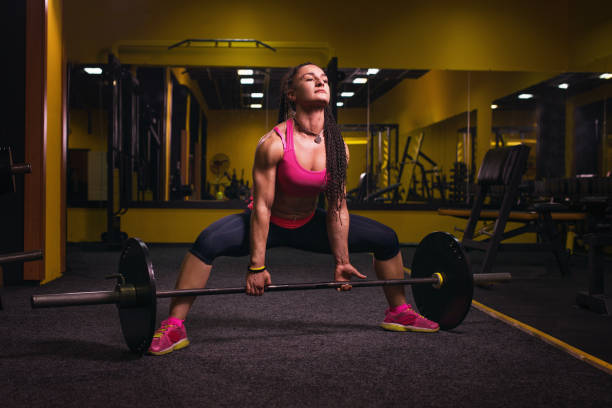 giovane donna che lavora sodo in palestra. adatta atleta femminile solleva pesi in health club. - picking up weight women sport foto e immagini stock