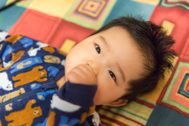 cute baby in bed - thumb sucking cute small lying down imagens e fotografias de stock