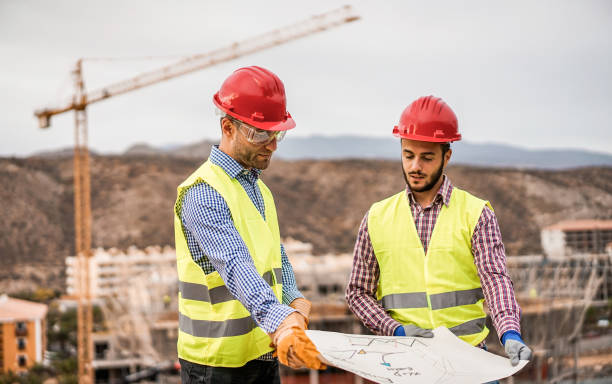 Builders on residential construction site looking the building project  - Workers are satisfied of their plan - Dealing, real estate, engineer and industrial concept - Focus on left man face