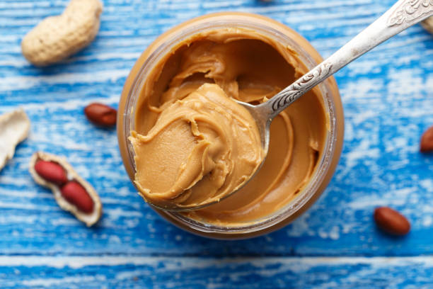 istock peanut butter in an open jar on a blue wooden background 927410660