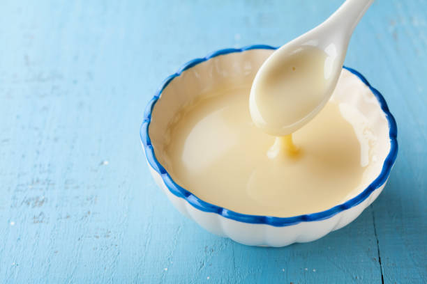 Bowl with pouring condensed milk or evaporated milk. stock photo