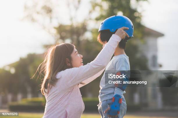 그녀의 아들을 돕는 아시아 어머니 블루 헬멧에 착용 즐기는 시간 함께 공원에서 보호에 대한 스톡 사진 및 기타 이미지 - 보호, 아시아, 아이