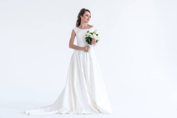 belle mariée brune posant dans une robe blanche avec le bouquet de la mariée, isolé sur blanc - robe de mariée photos et images de collection