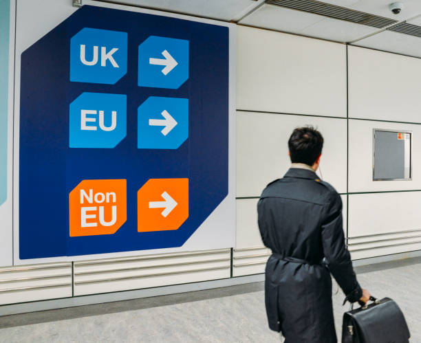 Passenger walks past sign prior to immigration control pass a sign pointing towards queues for UK, EU and Non-EU passport holders. In April 2019, UK is set to leave the European Union - Brexit theme stock photo