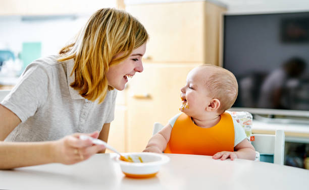 母親�と赤ちゃんが食事中に笑っています。 - baby eating child mother ストックフォトと画像