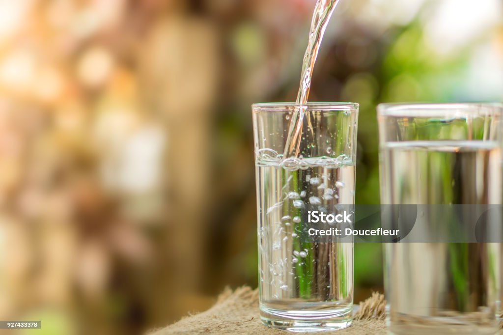 Pouring fresh water on drinking glass over nature sunlight morning background Pouring fresh water on drinking glass over nature sunlight morning ,freshness concept background Water Stock Photo