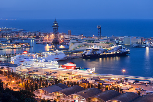 City of Barcelona at night in Catalonia, Spain, ships docked at cruise port terminal on Mediterranean Sea.