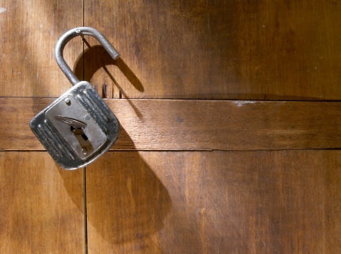 Antique padlock with key hanging  on wooden door