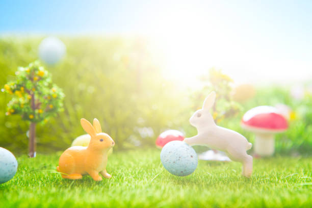 istock Little Easter bunny toys and Easter eggs on green grass 927444766