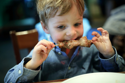Child biting kebab in an asian restaurant